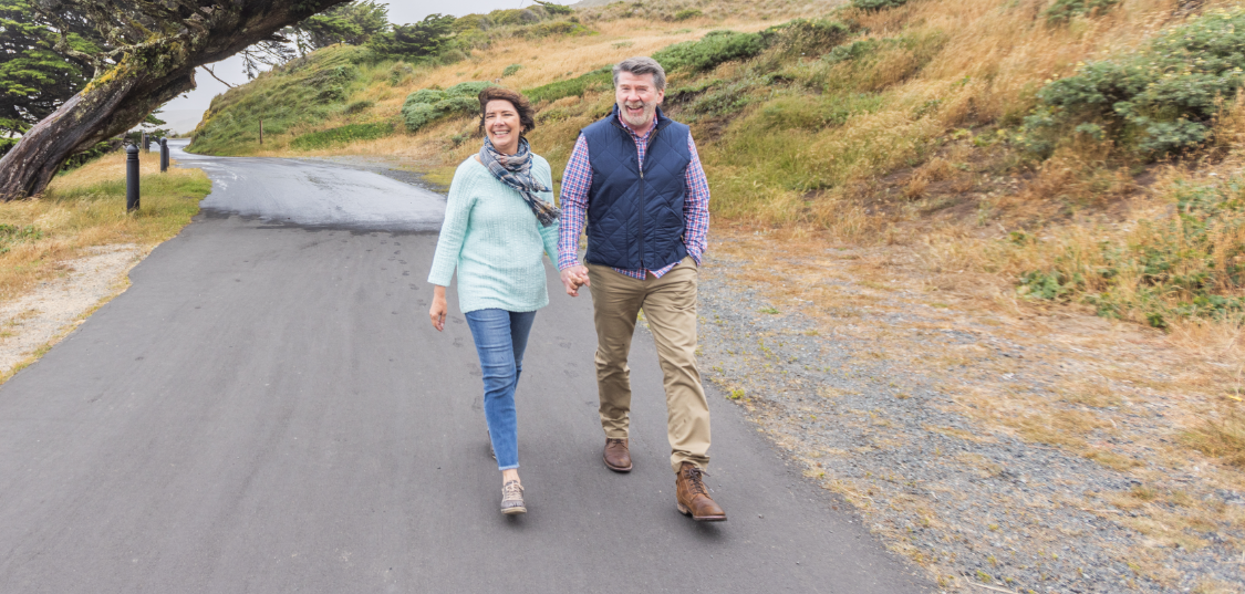 Older couple walking hand in hand on a road together