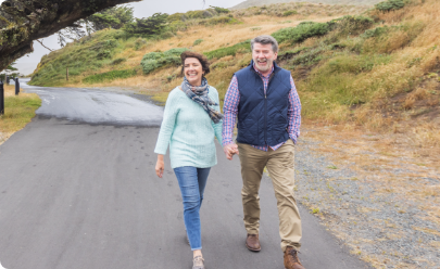 Older couple walking hand in hand on a road together