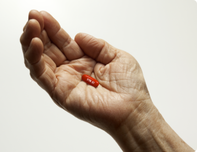 A person holding VYNDAMAX (tafamidis) capsule, capsule pictured is not actual size