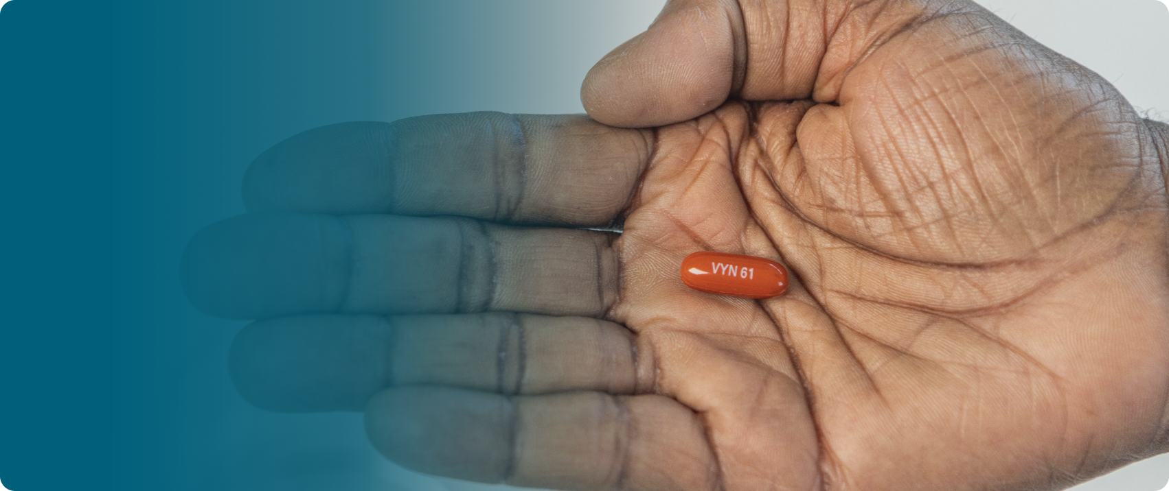 A hand with palm facing up holding a VYNDAMAX (tafamidis) pill